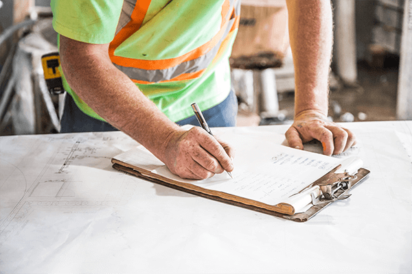 A person in a safety vest writing on a clipboard