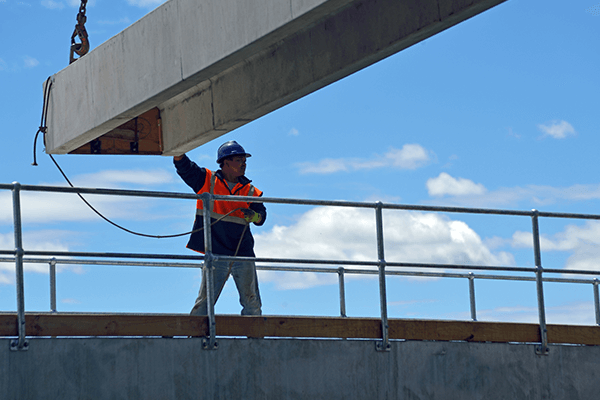 A person in a safety vest holding a metal beam